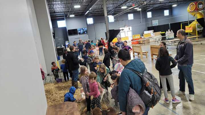 Children and families petting lambs during an Easter Egg Hunt event at The Warehouse community recreation center