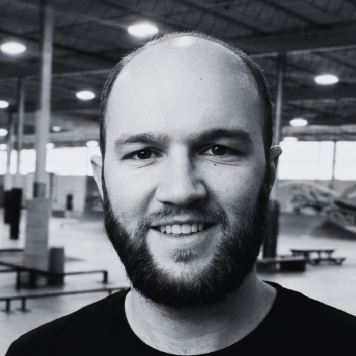 Headshot of Garrett Schopp, Board Member at The Warehouse, smiling with a short brown beard and close-cropped hair inside an indoor skatepark facility.