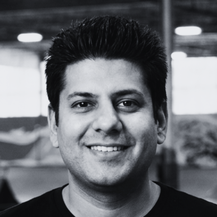 Headshot of Anany Maini, Secretary-Treasurer of the Board of Directors at The Warehouse, smiling with short, spiked dark hair inside an indoor skatepark facility.