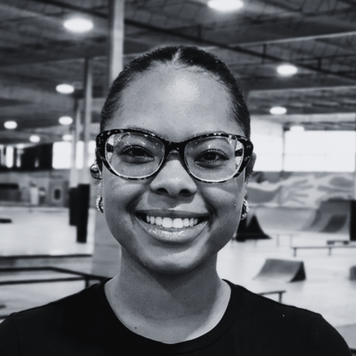 Headshot of Seionna, Event Coordinator at The Warehouse, smiling warmly while wearing cat-eye glasses inside an indoor skatepark facility.