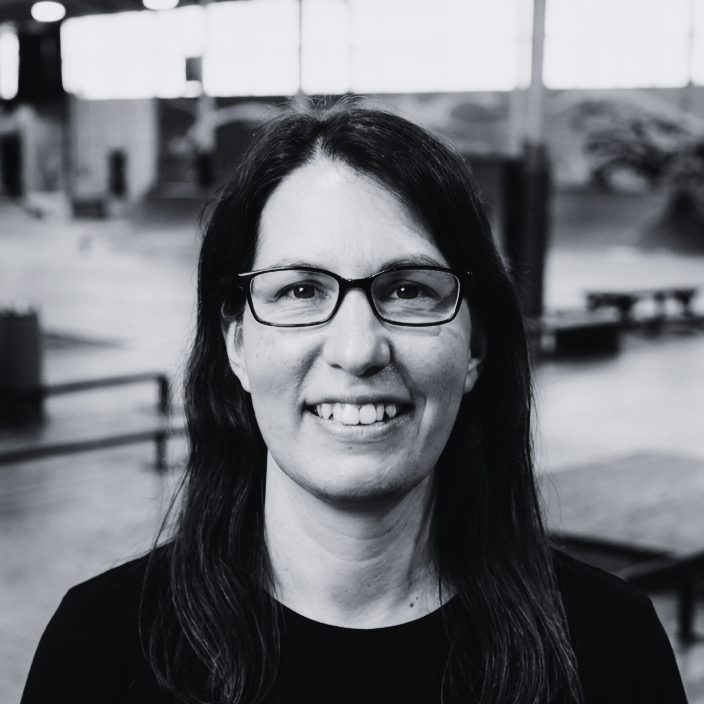Headshot of Jessica Utterback, Art Director at The Warehouse, smiling in front of the blur and ramp structures of an indoor skatepark.
